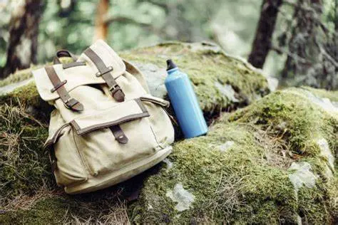Mochila con elementos esenciales para un tour: botella de agua, cámara, sombrero.